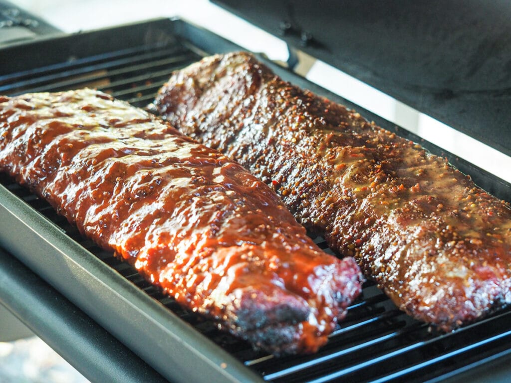 ribs with bbq sauce cooking on smoker