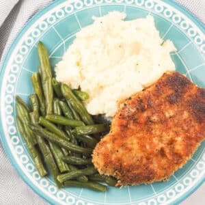 parmesan crusted pork chops on light blue plate with sides