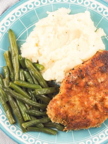 parmesan crusted pork chops on light blue plate with sides