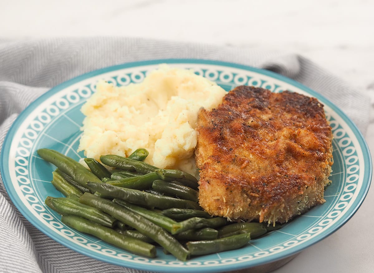 parmesan pork chops on plate with sides