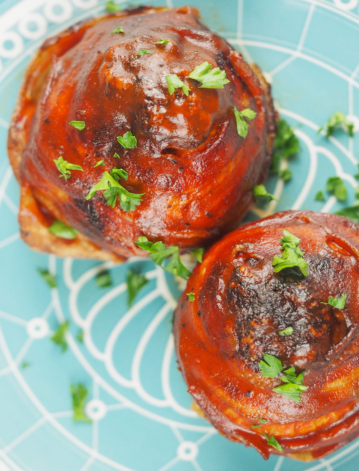 bacon onion bombs sprinkled with parsley on light blue plate with white designs
