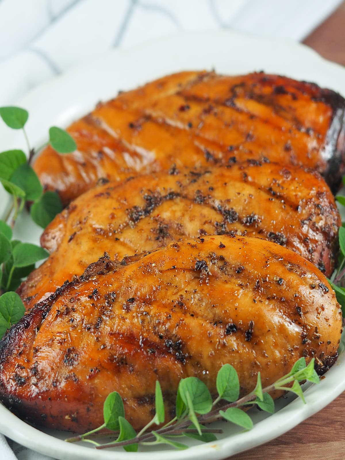 grilled chicken breasts on platter with fresh oregano
