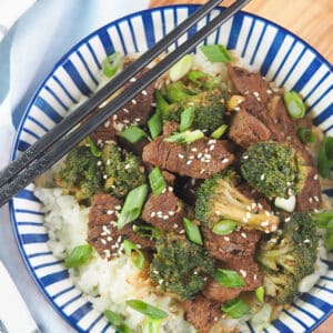 beef and broccoli on rice with chopsticks