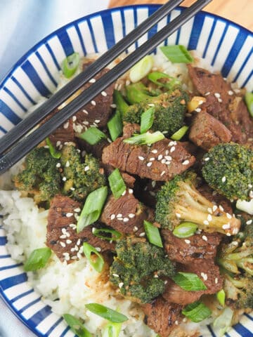 beef and broccoli on rice with chopsticks
