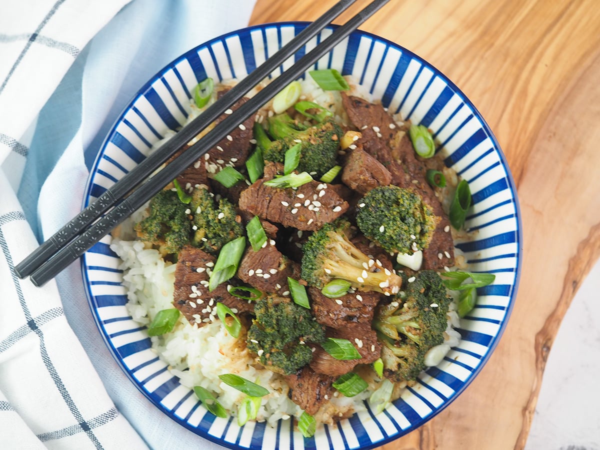 beef and broccoli on rice in blue and white striped bowl