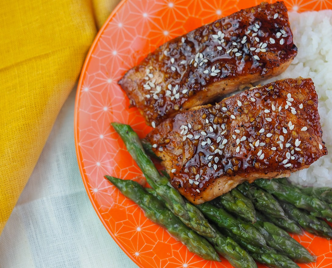 glazed salmon on orange plate with rice and asparagus