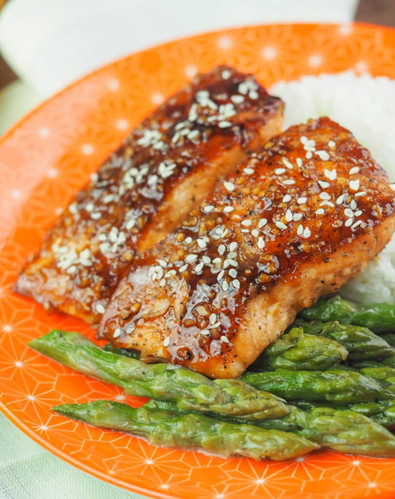 honey soy glazed salmon on orange plate with rice and asparagus