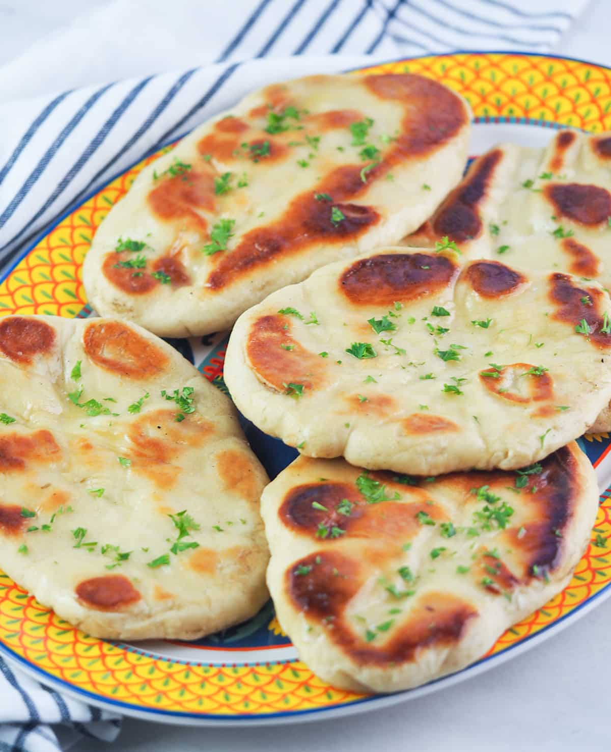 Naan bread on yellow rimmed platter with red and green scallop designs