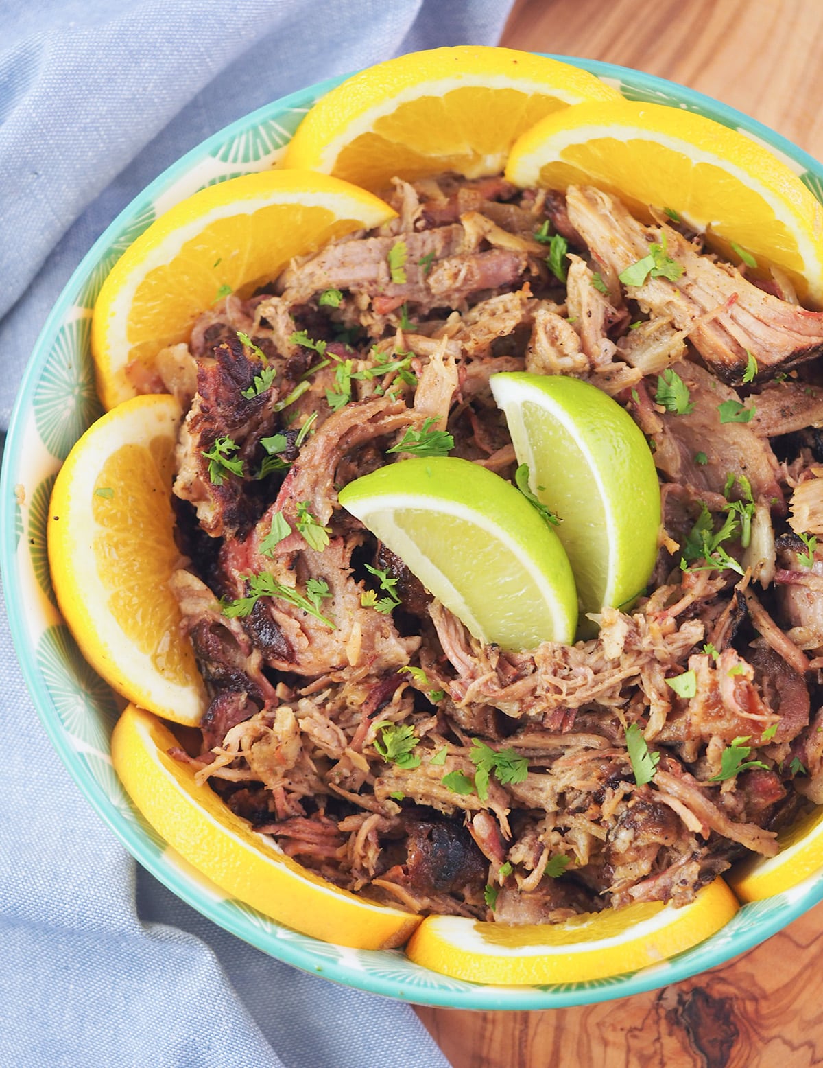 shredded mojo pork in bowl with citrus slices