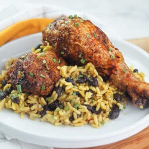 Grilled chicken legs on a bed of rice with black beans.