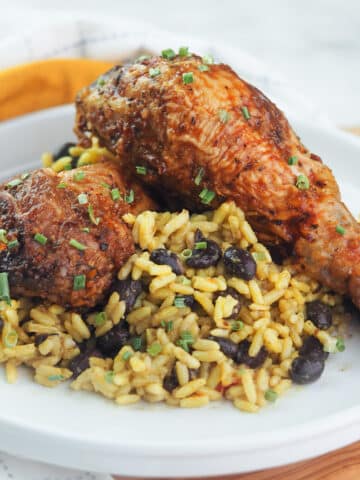 Grilled chicken legs on a bed of rice with black beans.