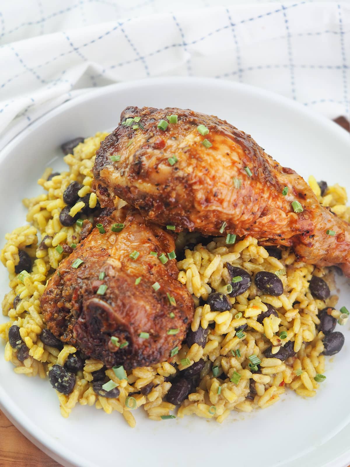 vertical chicken legs on yellow rice with black beans on white plate