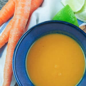Habanero sauce in blue bowl next to carrots.