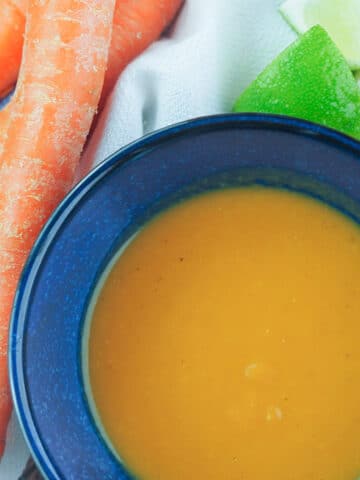 Habanero sauce in blue bowl next to carrots.